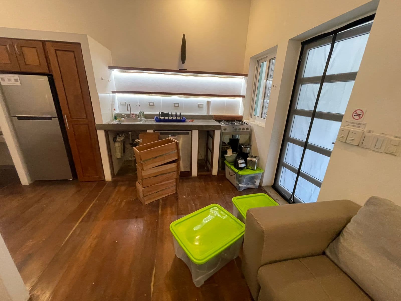 A partially furnished kitchen area with storage boxes and a couch.
